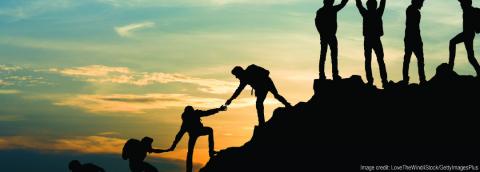 image with silhouette of people helping each other up a mountain