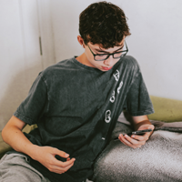 photo of teen Latinx male looking at cell phone screen while having a teleconference